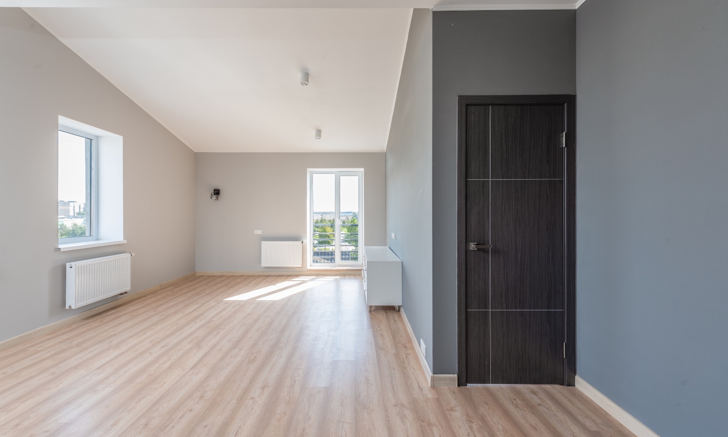 Spacious, newly remodeled room with light wood flooring and modern grey walls, highlighting the quality craftsmanship of Bayside Builders Group in the Bay Area.