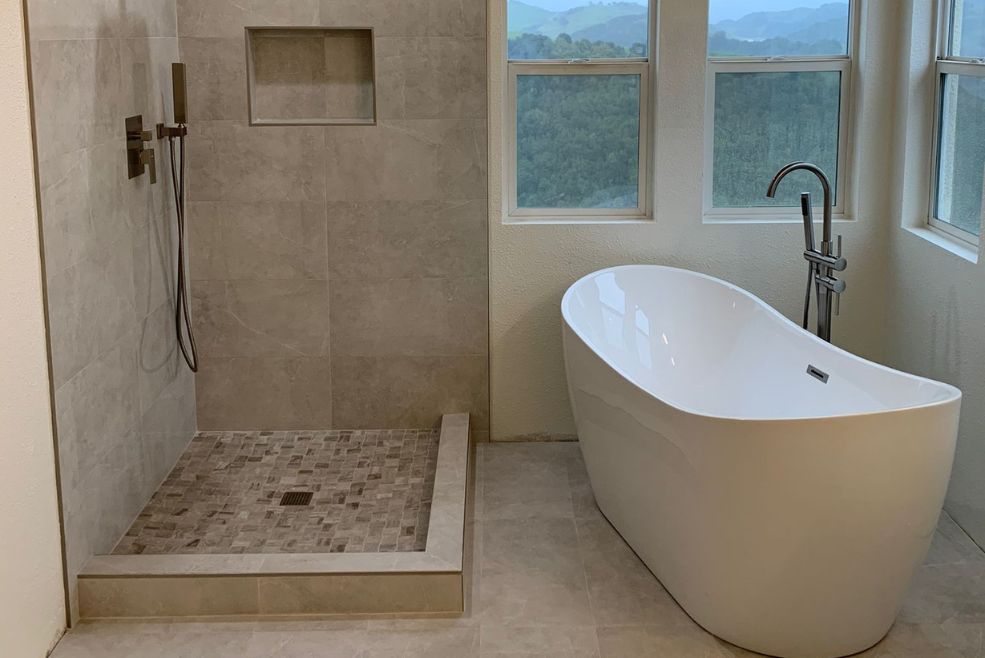 Luxurious Bay Area bathroom renovation featuring a freestanding bathtub and a modern tiled shower, showcasing Bayside Builders Group's expertise in home remodeling and design.